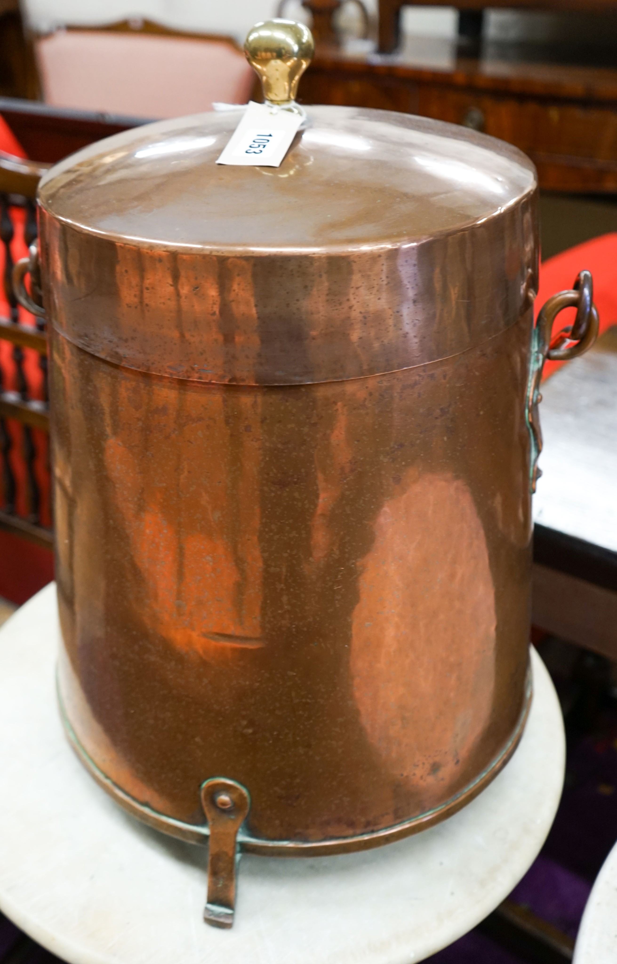 A Dutch copper milk churn and cover, having brass knop finial and swing handle on three feet, height 55cm